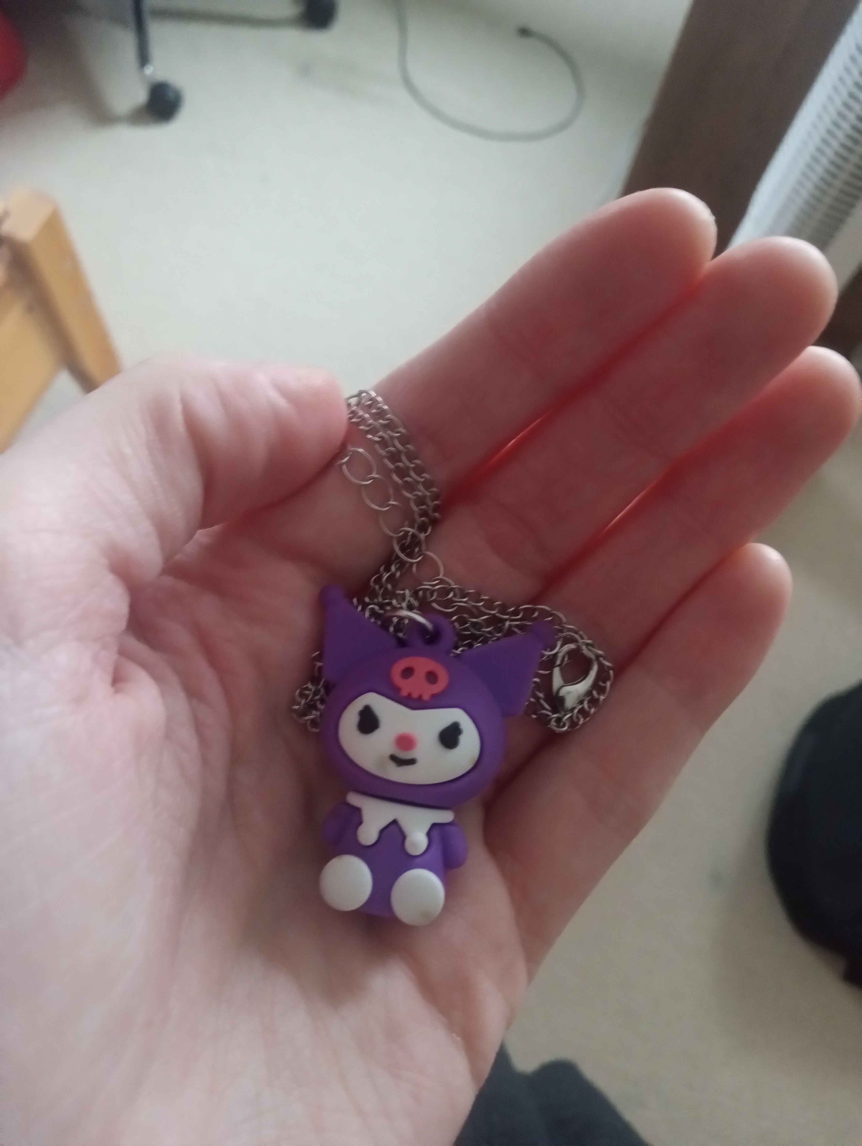 a charm of kuromi on a veryyy long chain that is all piled in my hand